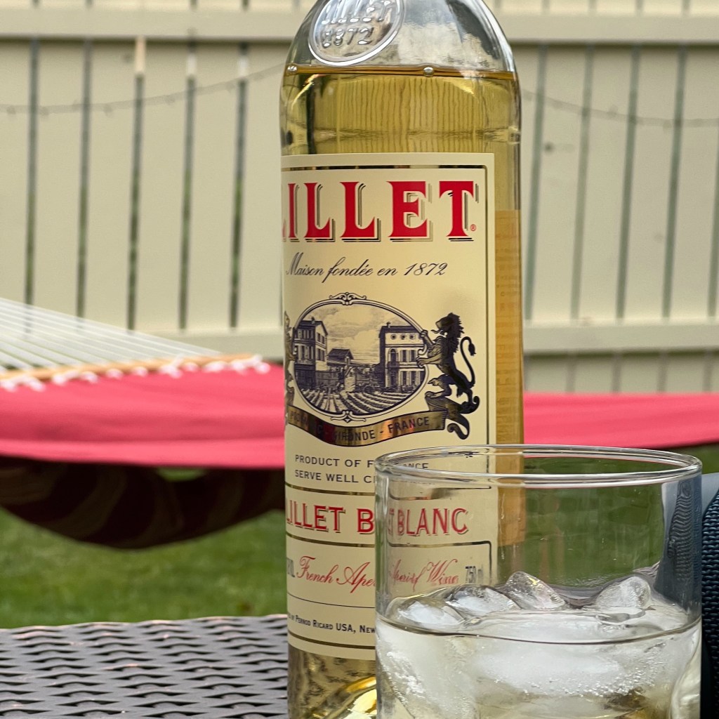 photo of a glass of wine with lillet bottle next to the cup.