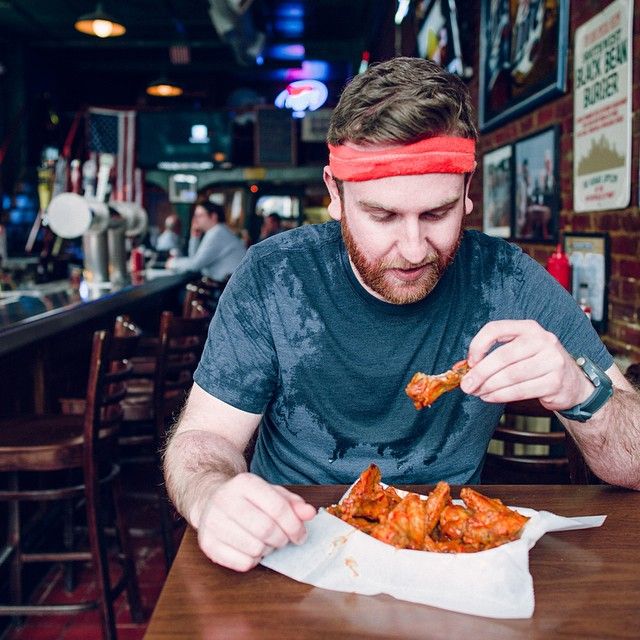 A man eating wings sitting at Primanti Brothers